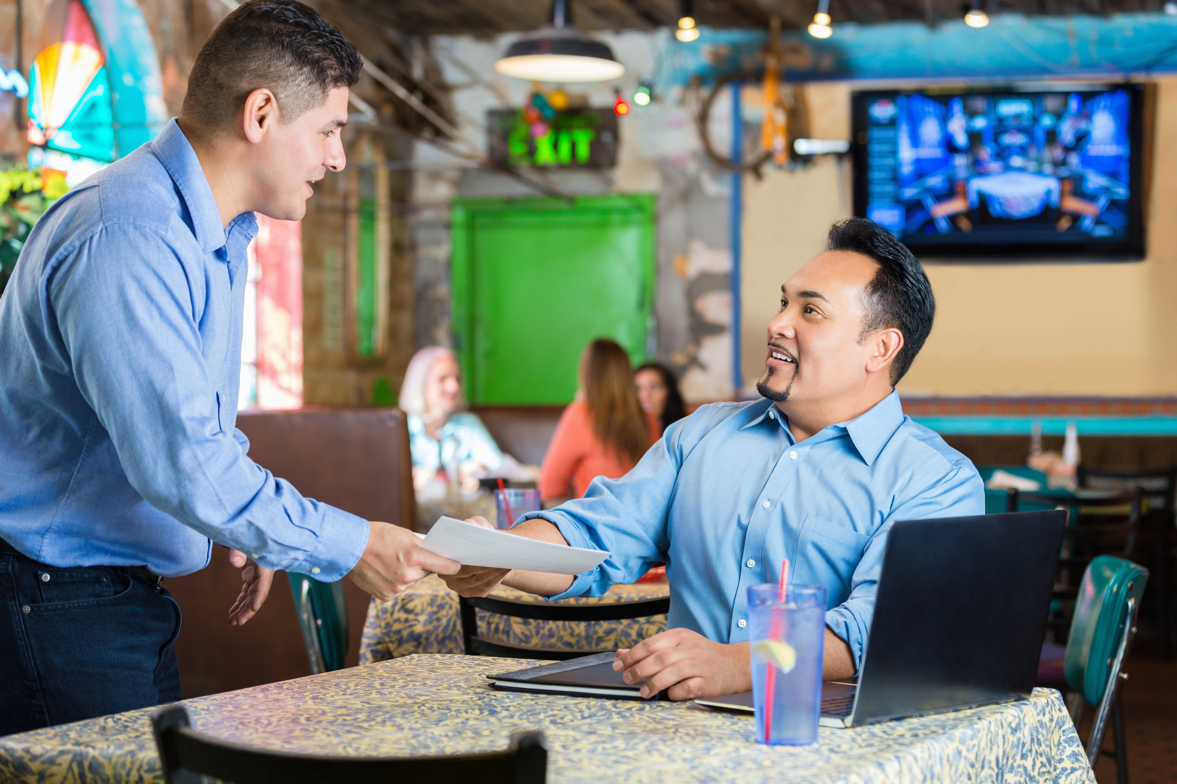 Young Hispanic man presenting resume during interview with restaurant manager