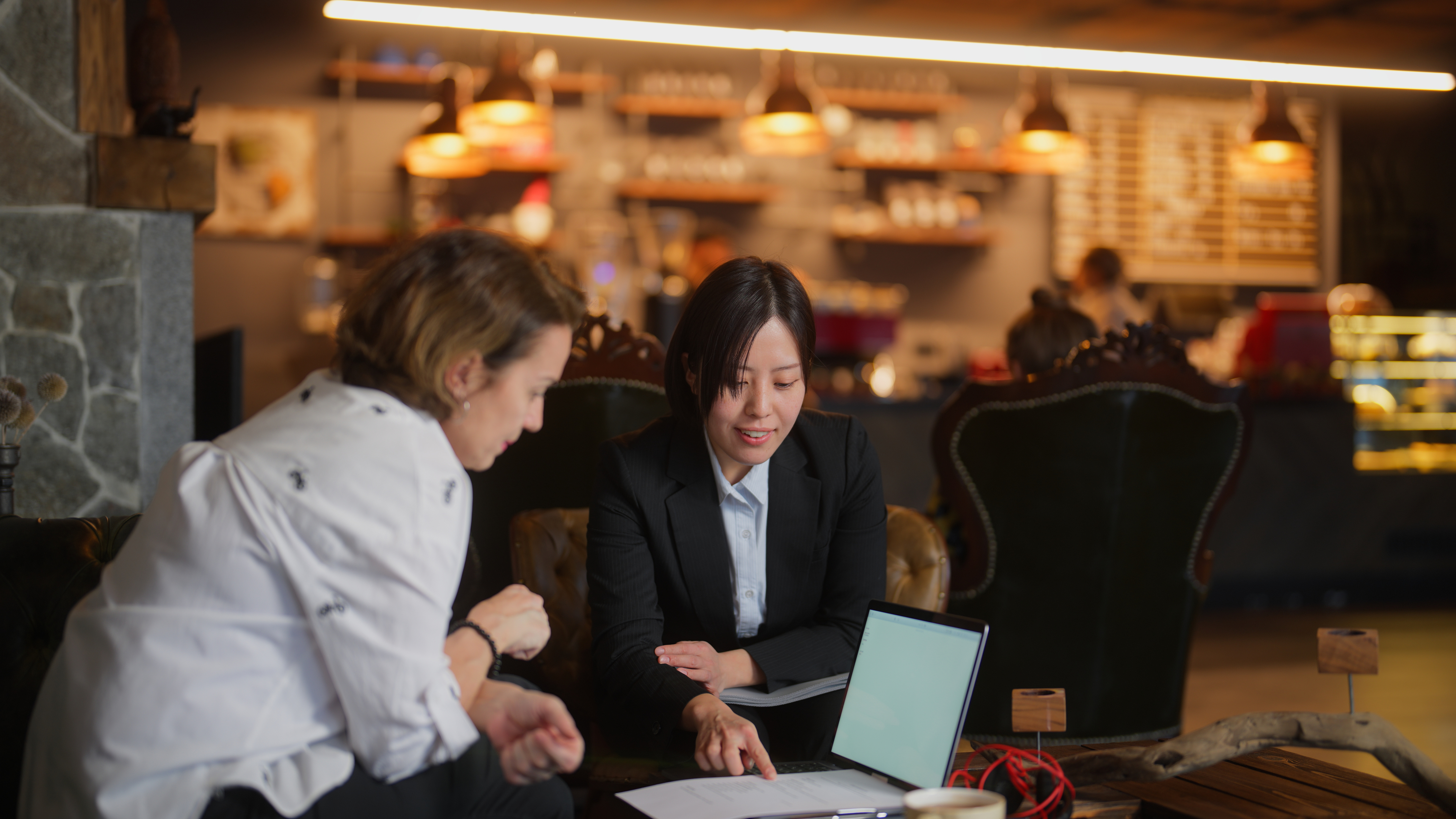 Two businesswomen are meeting each other in a cafe for a job interview.