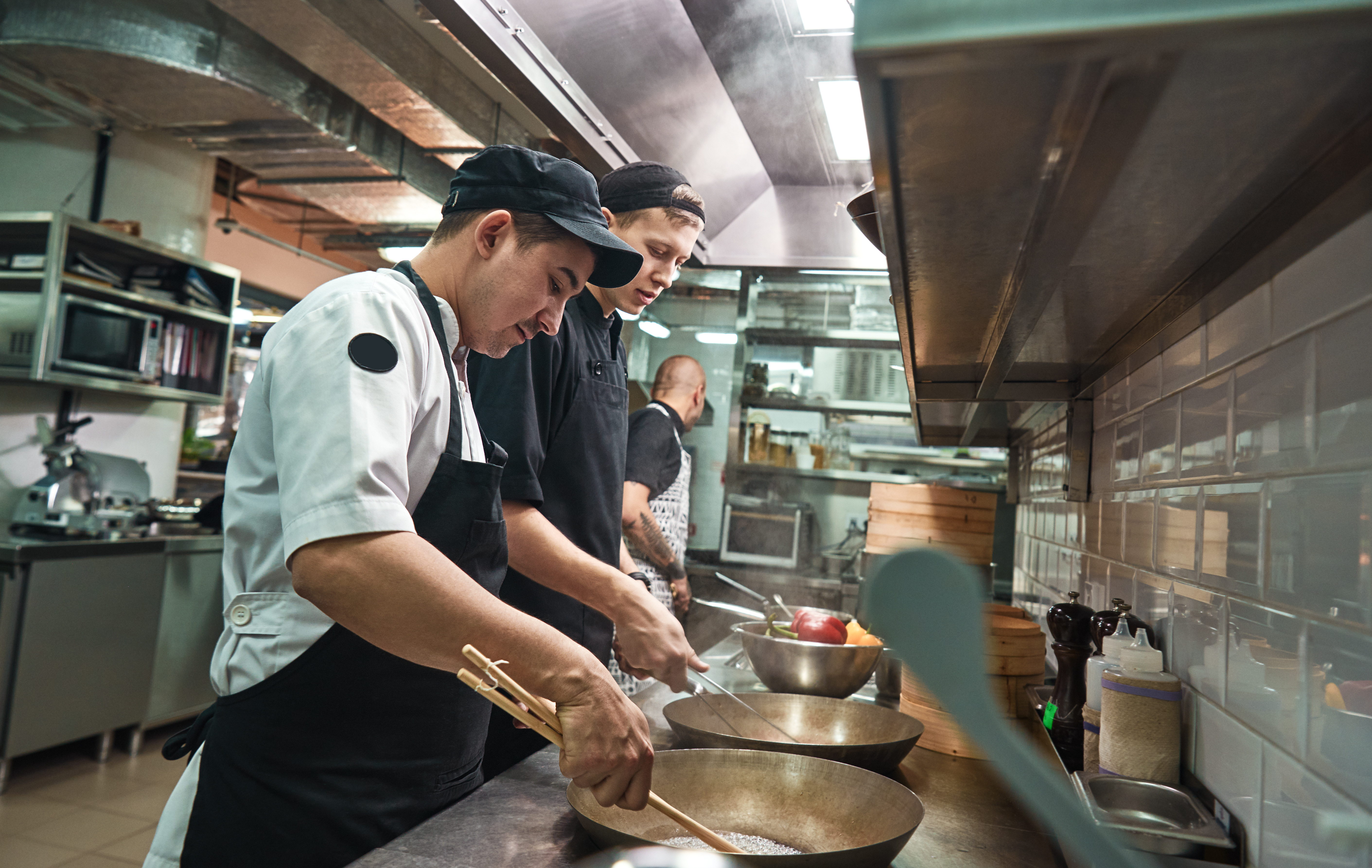 Two chef assistants cooking a new dish in a restaurant kitchen
                                           